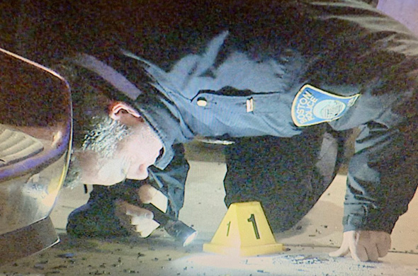 Officer looking for evidence at shooting scene on Crawford Street in Roxbury