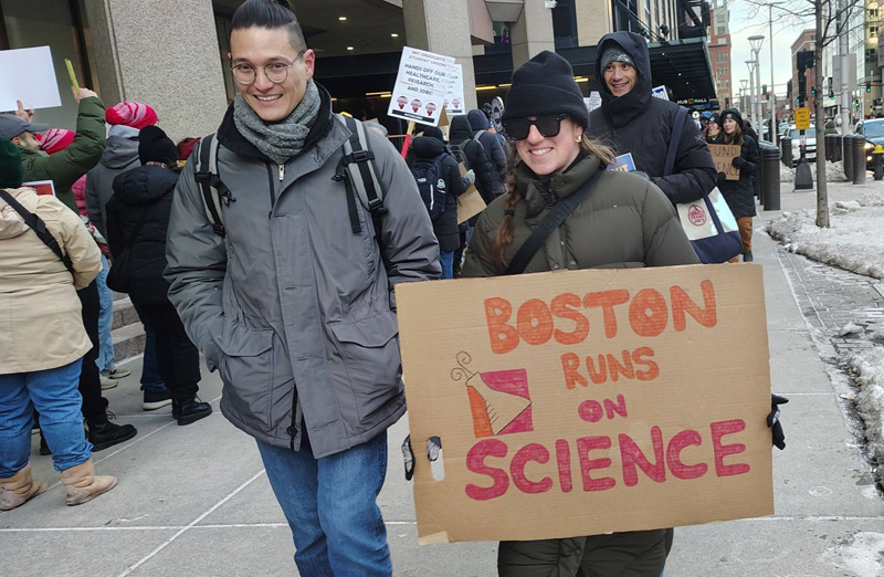 Protester holding a sign that says Boston runs on Science