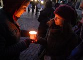 People holding a protest candle in front of the State House