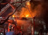 House on fire on Draper Street, with firefighters on what's left of the front porch