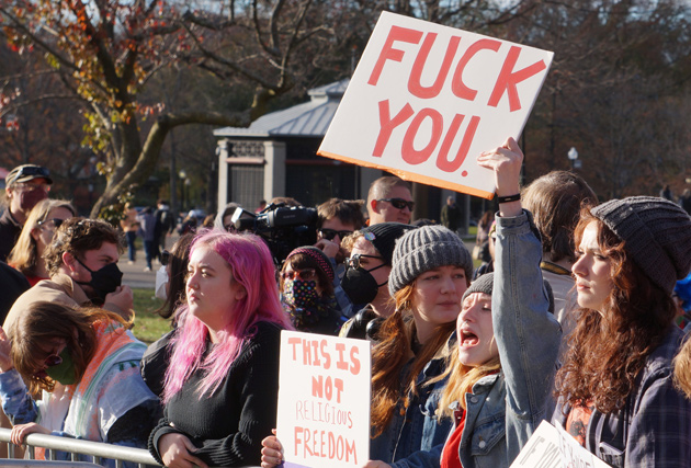 Woman holding sign telling forced birthers to fuck off