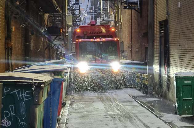 Trash truck in an alley in the snow